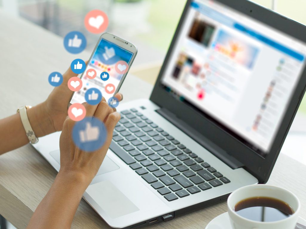 Laptop and phone with likes and hearts popping out